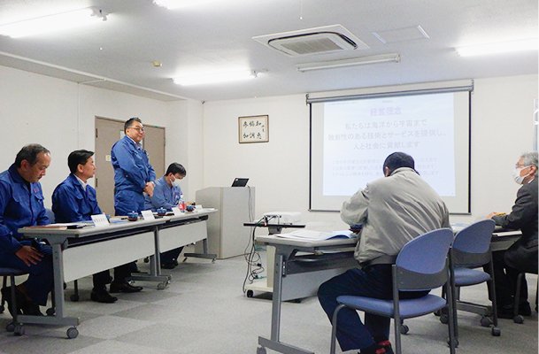 This shows a discussion taking place in a small-to-medium-sized conference room, with materials being projected onto a screen.