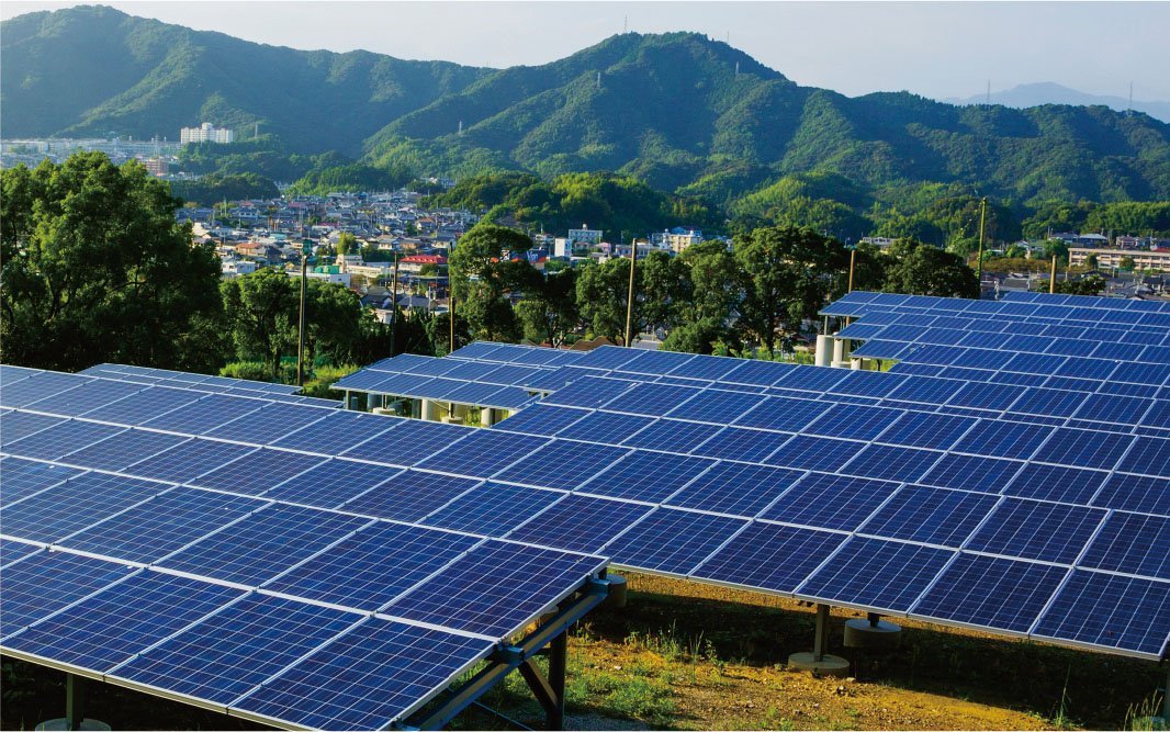 山間部にほど近い屋外に設置された太陽光発電のパネルを写した写真です。