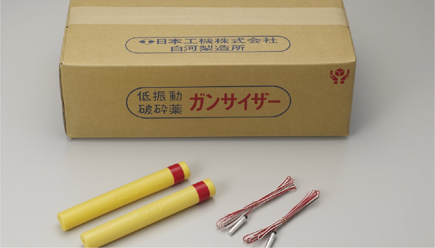ガムテープで封をした段ボールが1箱おいてありその下側に黄色い筒に赤いテープをした製品2本と導火線2組が並べられています。