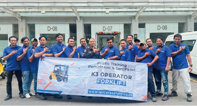 This is a group photo of 16 employees. Several people in the front row are holding a banner that reads 