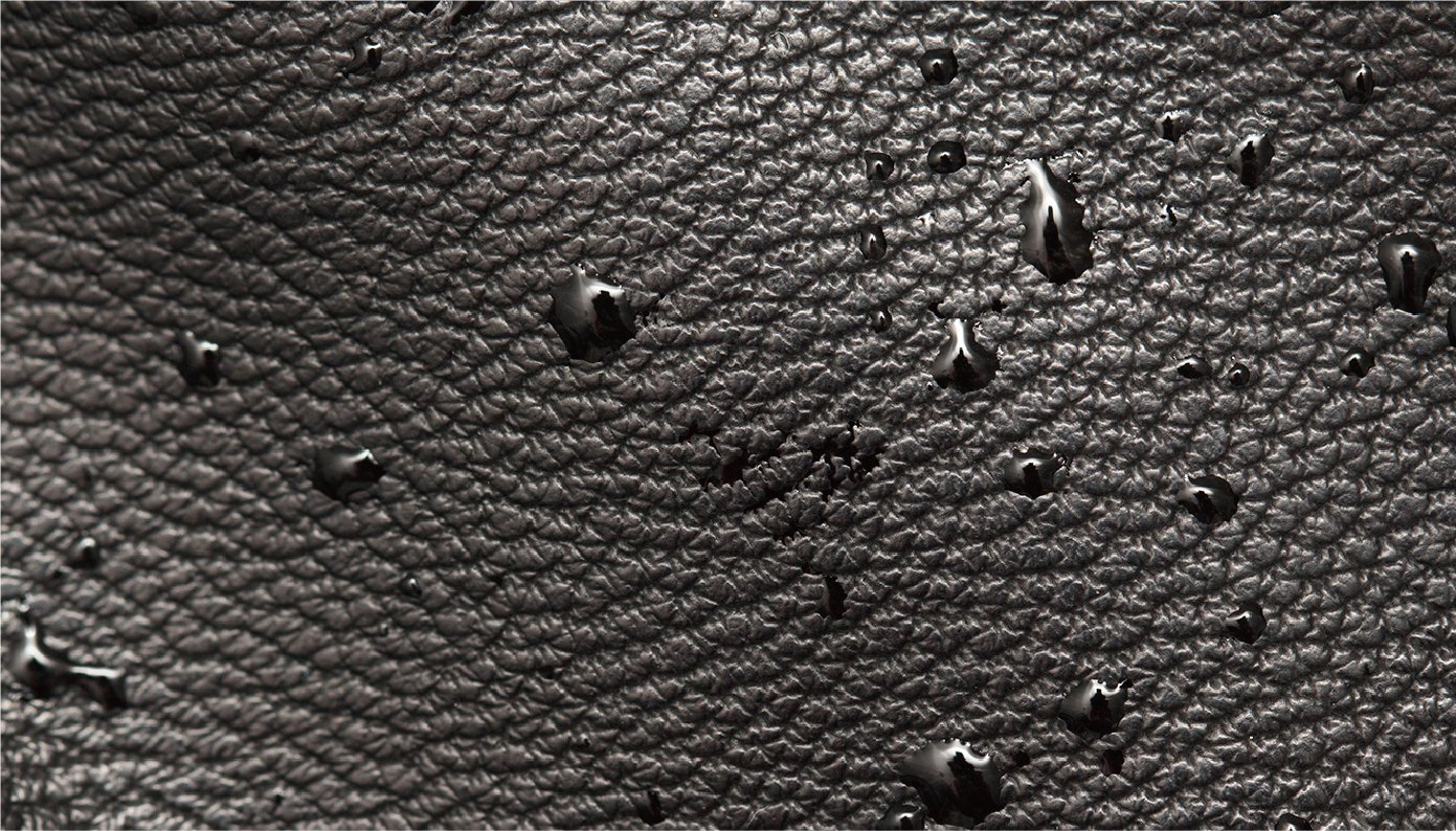 The surface of this black rubber-like sheet, which looks like a collection of small grains, is uneven and repels water, so it is covered in many water droplets.