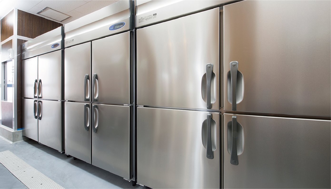 There are three large commercial refrigerators lined up, each with four doors (two on the top and two on the bottom) that open outwards.
