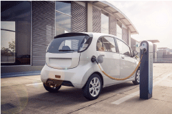 白いコンパクトカーの電気自動車が充電器から充電しています。