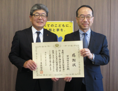 スーツの男性が2人で額に入った感謝状を持って記念撮影をしています。