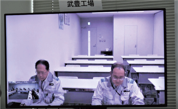 全社合同防災訓練で、工場と本社をオンラインで接続した報告訓練で大型スクリーンに写された工場関係者の映像です。
